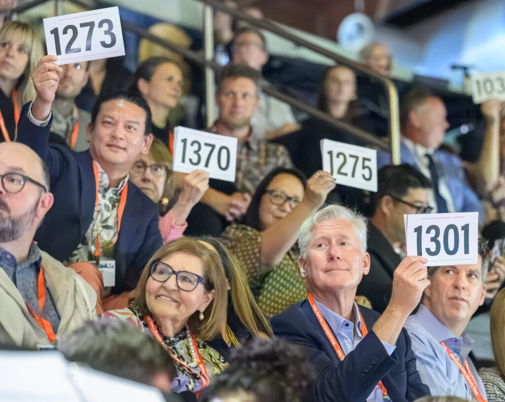 people raising paddles during a live auction