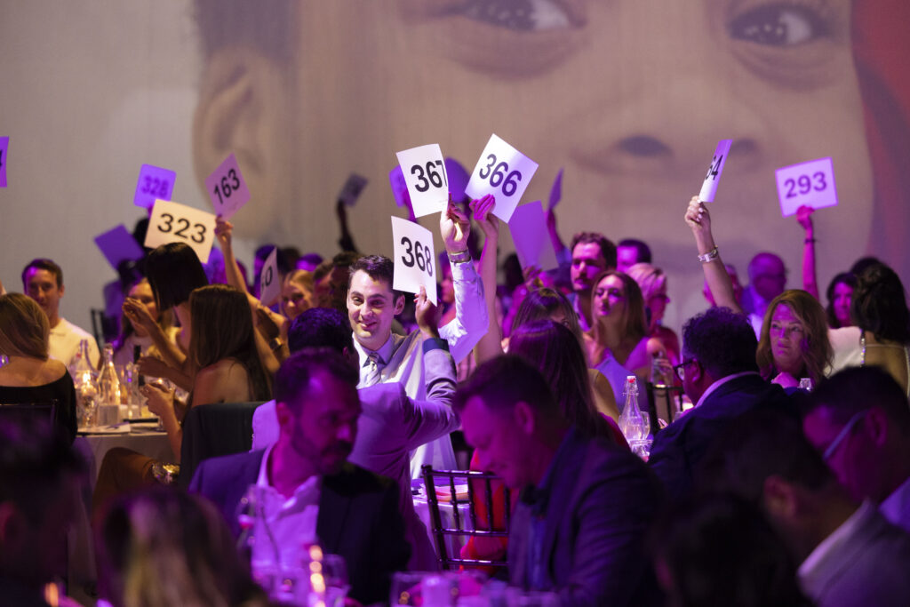 people raising paddles during a live auction