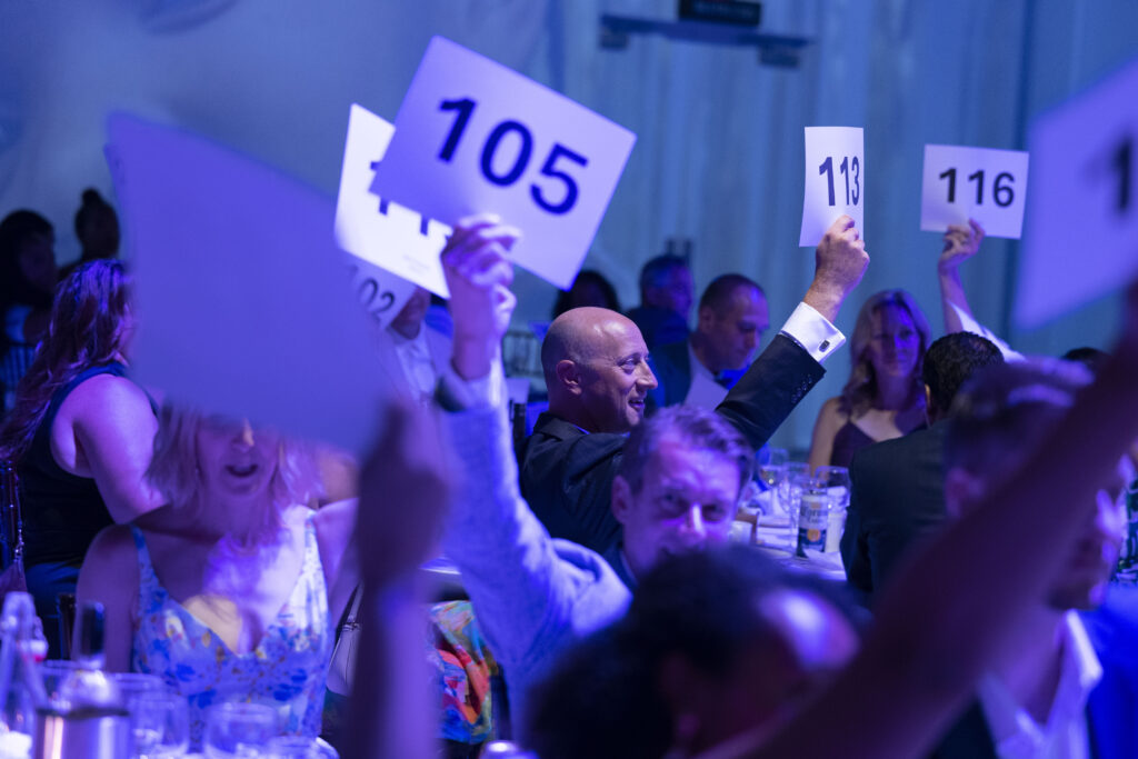 people raising paddles during a live auction